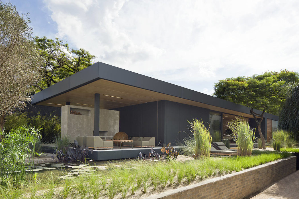 Sleek house with flat roof, expansive patio, and lush garden.