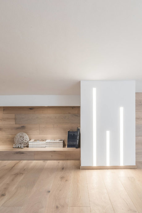 Modern room with wooden floor and a lit LED panel door.