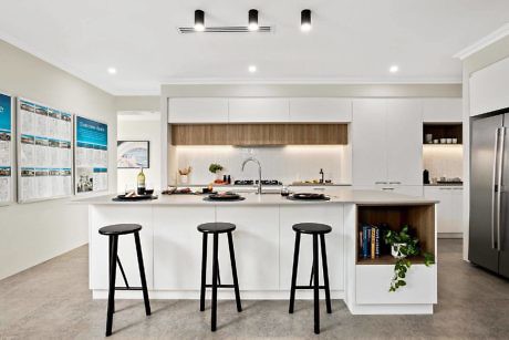 Modern kitchen with white cabinetry, wooden accents, and black stools.