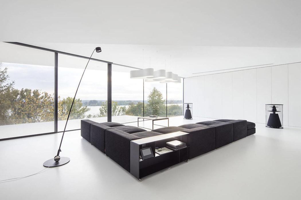 Minimalist living room with large windows overlooking a lake.