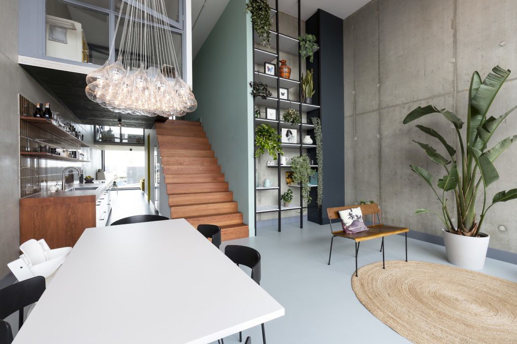 Contemporary kitchen with concrete walls, wooden stairs, and hanging plants.