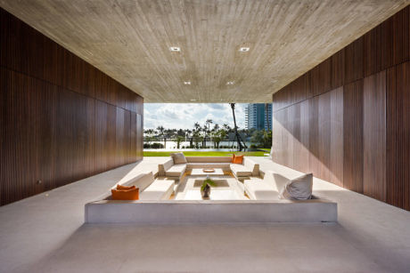 Contemporary open-air lounge with wooden walls and concrete ceiling.