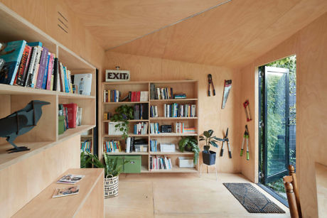 Wood-paneled room with bookshelves, a window, and garden tools.