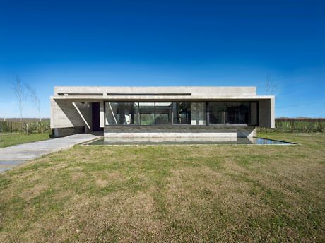 Modern single-story concrete house with large windows and a flat roof.