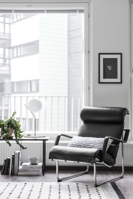 Modern black leather chair by a window in a bright room with minimal decor.