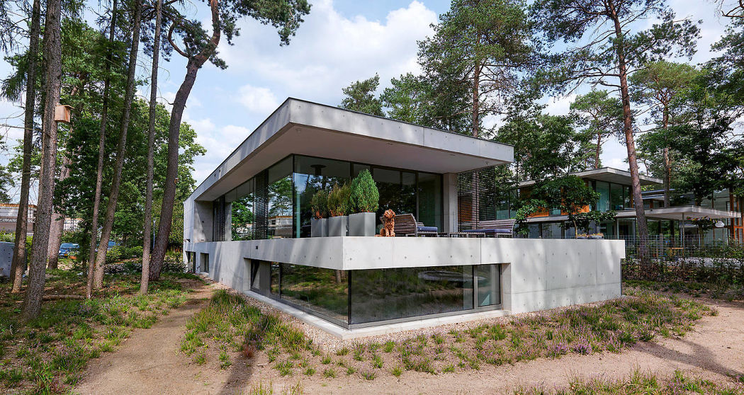 Contemporary forest house with expansive glass walls and a cantilevered upper level