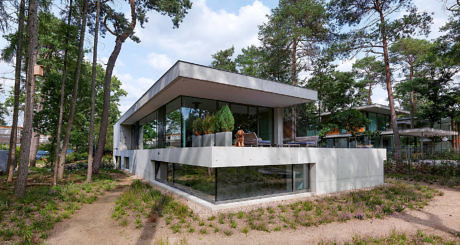 Contemporary forest house with expansive glass walls and a cantilevered upper level