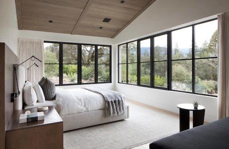 Modern bedroom with large windows and nature view.