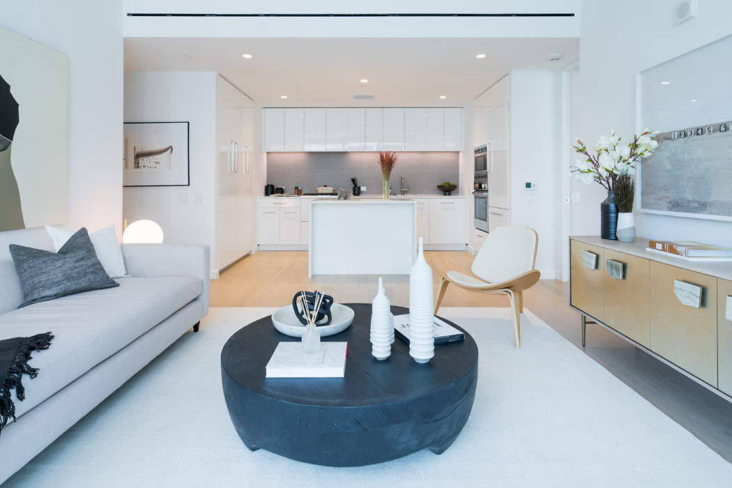 Modern living room with white kitchen in the background.