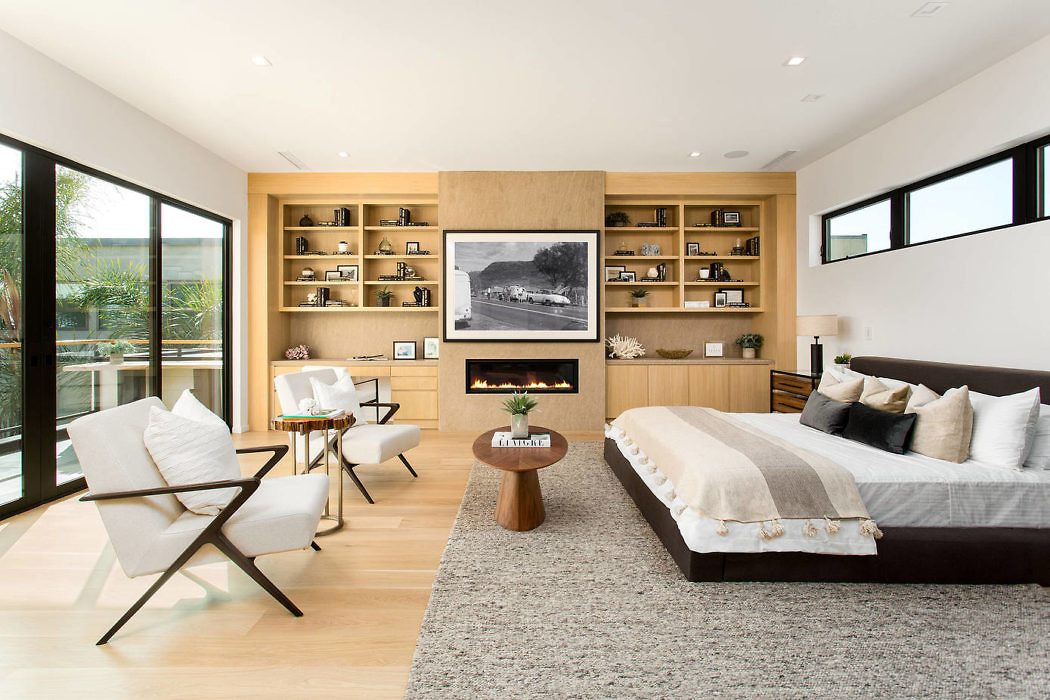 Modern bedroom with built-in shelving, fireplace, and large windows.