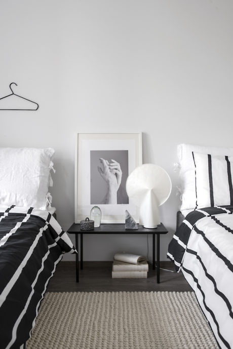 Minimalist bedroom with monochrome stripe bedding and wall art.