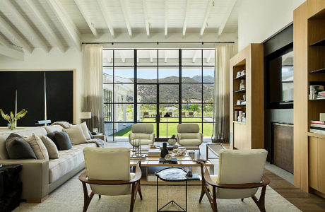 Modern living room with large windows overlooking mountains.