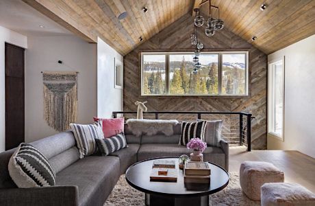 Contemporary living room with large window and wooden ceiling.