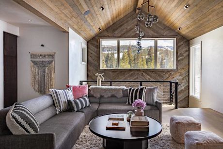 Contemporary living room with large window and wooden ceiling.