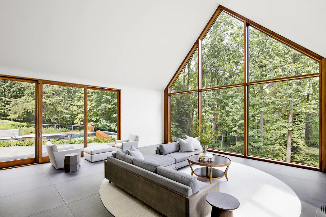 Modern living room with large windows overlooking a forest.