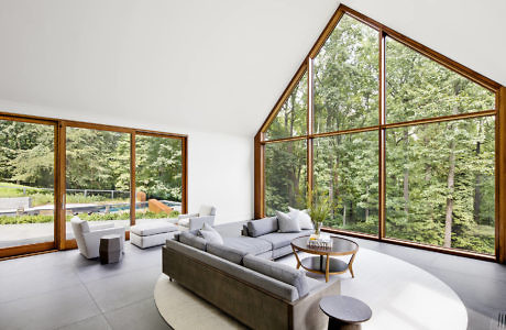 Modern living room with large windows overlooking a forest.