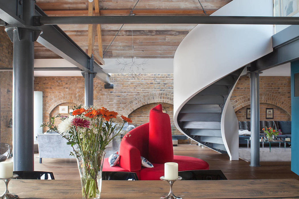 Industrial loft with a spiral staircase and exposed beams.