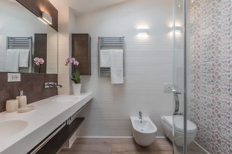 Modern bathroom with double sink and patterned shower wall.