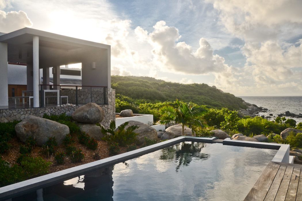 Modern seaside villa with infinity pool at sunset.