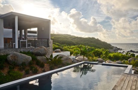 Modern seaside villa with infinity pool at sunset.