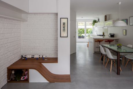 Modern dining room with white brick walls, wooden table, and concrete floor.