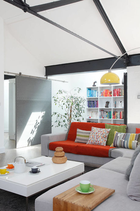 Bright living room with red sofa, white walls, and a yellow lamp.