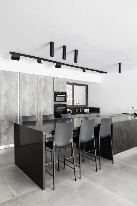 Monochrome kitchen with sleek bar stools and concrete accents.