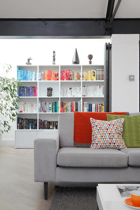 Contemporary living space with colorful bookshelf and grey sofa.