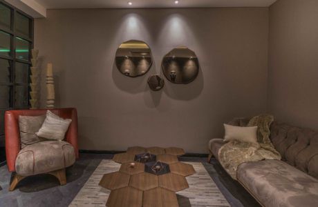 Modern living room with hexagonal center table, sofa, armchair, and wall