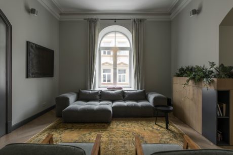 Elegant living room with a gray sofa, vintage rug, and tall curtains.