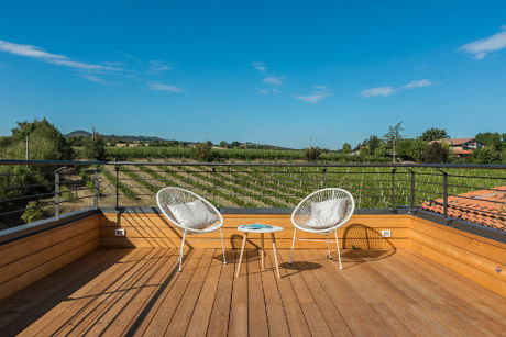 Rooftop deck with two white chairs, wooden floor, and countryside view