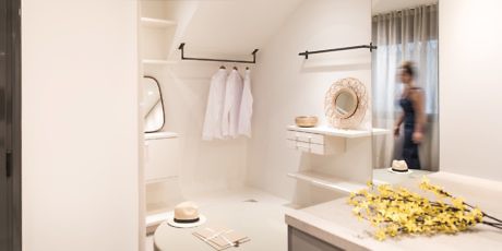 Modern walk-in closet with clothes and blurred person in the background.