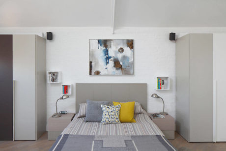 Modern bedroom with white walls, large bed, and abstract art.