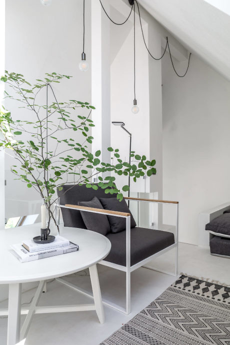 Modern minimalist interior with white walls, black sofa, round table and pendant lights.