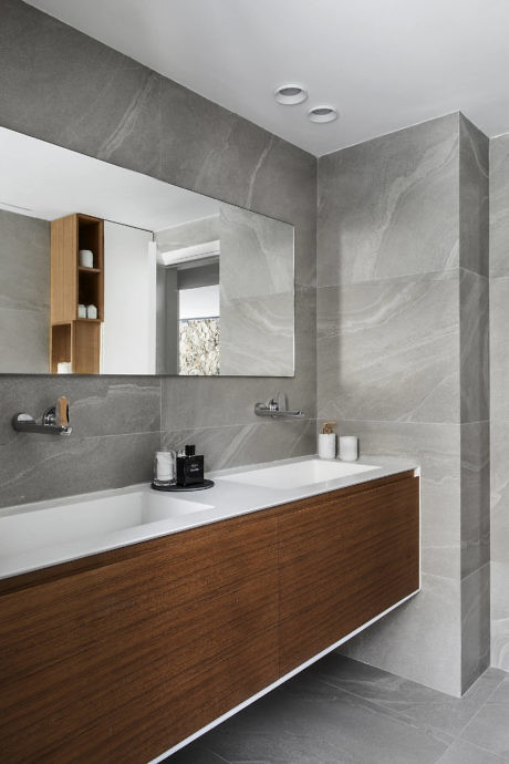 Modern bathroom with gray marble tiles and wooden vanity.