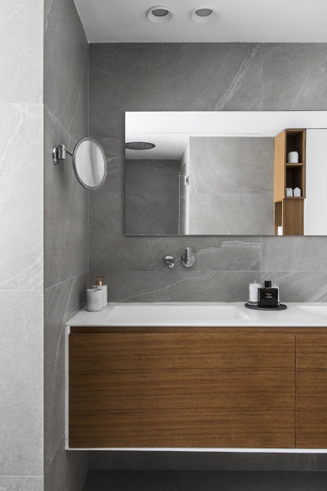Modern bathroom with gray tiles and wooden vanity.