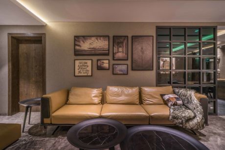 Contemporary living room with tan leather sofa, art wall, and glass doors.