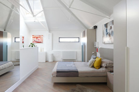Bright minimalist loft bedroom with slanted ceilings and skylights.
