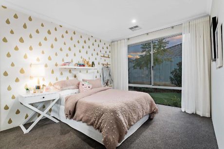 Contemporary bedroom with gold teardrop-patterned wallpaper and large window.