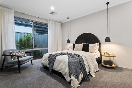 Contemporary bedroom with pendant lighting, plush bedding, and neutral tones.