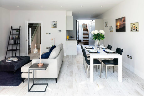 Modern living and dining room with white decor and wooden floors.