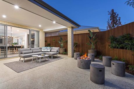 Contemporary outdoor patio with fire pit and seating area at dusk.