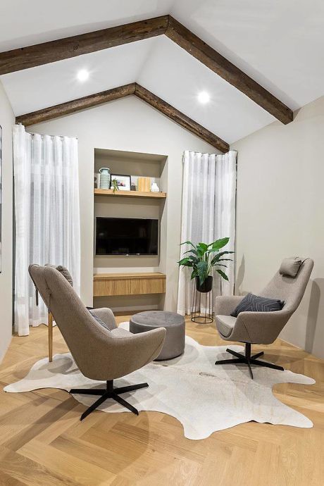 Modern living room with two chairs, wooden floors, and white curtains.