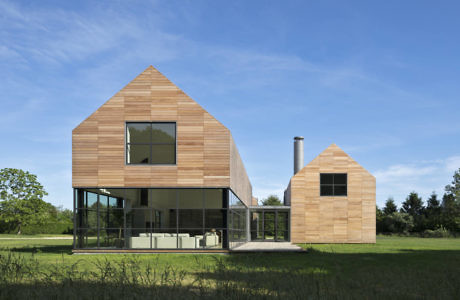 Modern wooden house with geometric design and large windows.