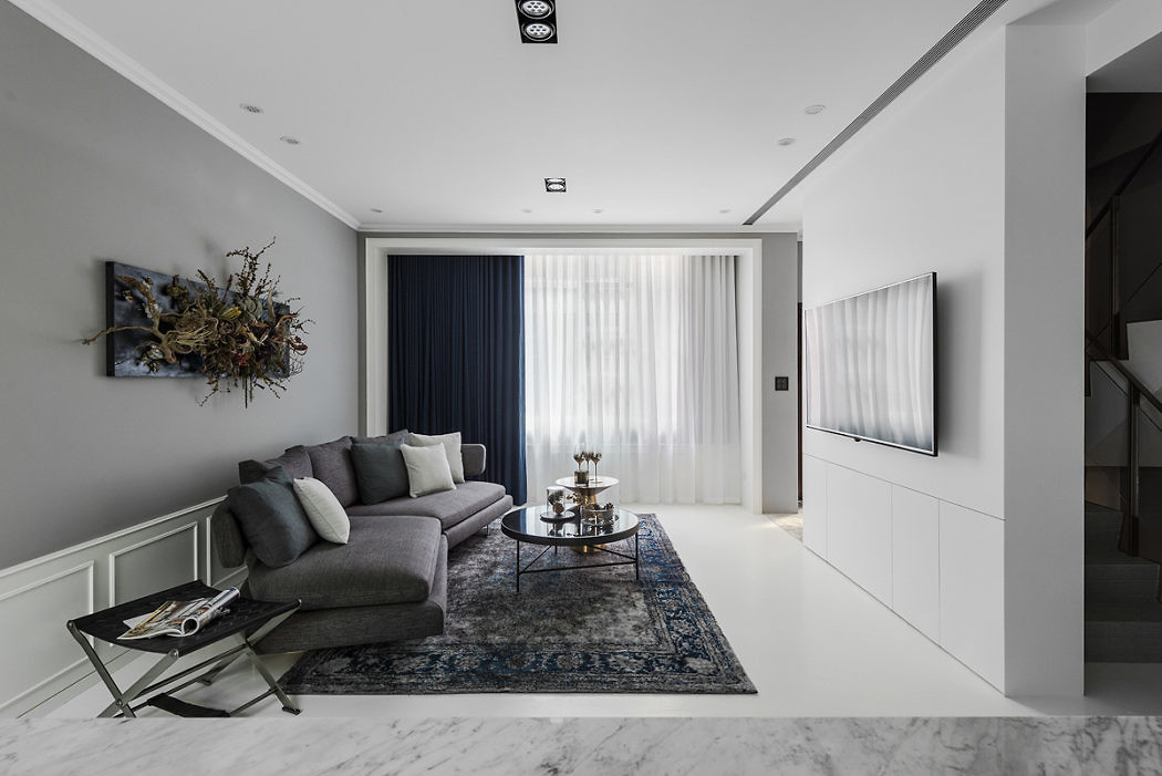 Contemporary living room with grey couch, blue rug, and sleek built-in cabinets