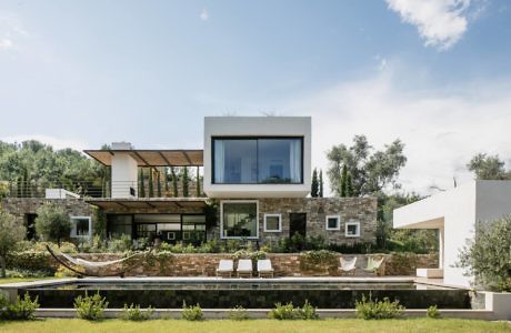 Modern two-story house with large windows and landscaped garden.