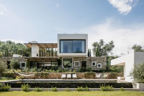 Modern two-story house with large windows and landscaped garden.