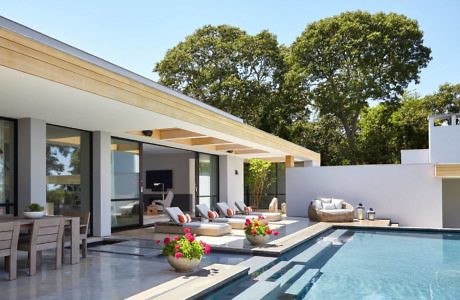 Modern house exterior with a pool, patio, and outdoor seating.