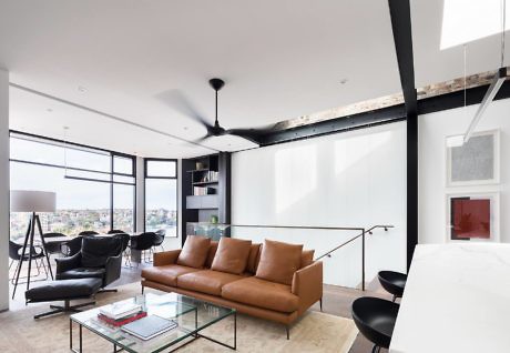 Modern living room with leather couch, glass coffee table, and city view.