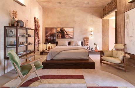 Earthy-toned bedroom with modern furniture and a patterned area rug.